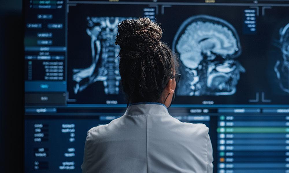 女神经学家看着电视屏幕, 分析脑扫描MRI图像, 为病人寻找治疗方法. 医疗保健神经科医生治疗人类.